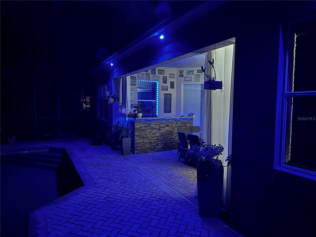 An outdoor patio area features a stone-faced bar, blue accent lighting, and a paved floor — 7511 HERITAGE GRAND PLACE, BRADENTON, FL