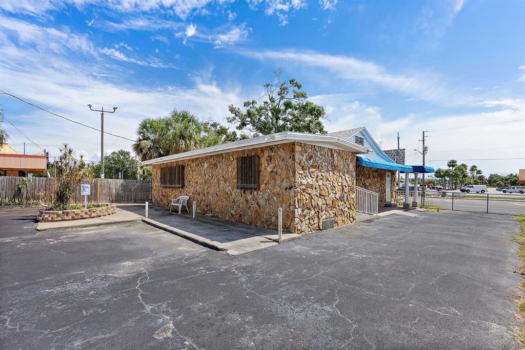 A stone-clad commercial building features a blue awning and a paved parking lot — 3425 22ND AVENUE S, ST PETERSBURG, FL