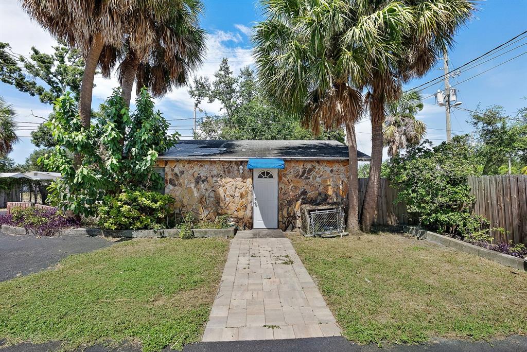 A small stone-clad house with a white door and a blue awning under palm trees — 3425 22ND AVENUE S, ST PETERSBURG, FL