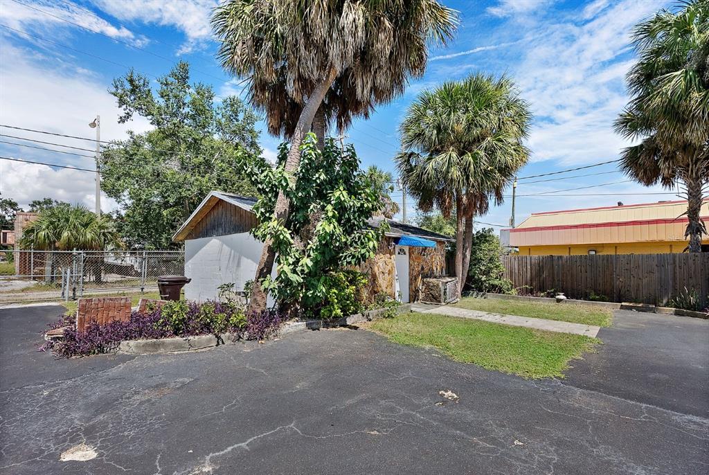 A small, stone-walled building with a blue awning sits beside palm trees and asphalt — 3425 22ND AVENUE S, ST PETERSBURG, FL