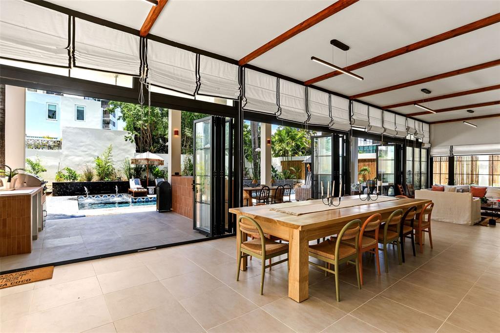 An open-concept dining area features a long wooden table, tile flooring, and folding glass doors — 2061 CACIQUE, SAN JUAN, PR