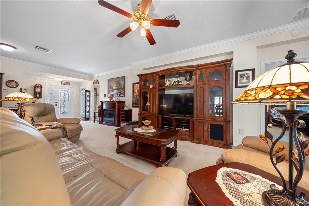 A living room features beige leather furniture, a wooden entertainment center, and a ceiling fan — 9203 SE 118TH LOOP, SUMMERFIELD, FL