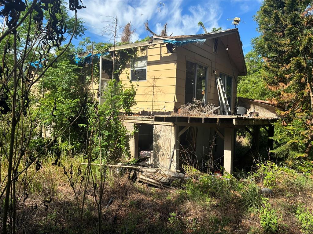 A weathered, two-story house with a damaged roof and an elevated wooden deck — 3752 N ORANGE BLOSSOM TRAIL, MOUNT DORA, FL