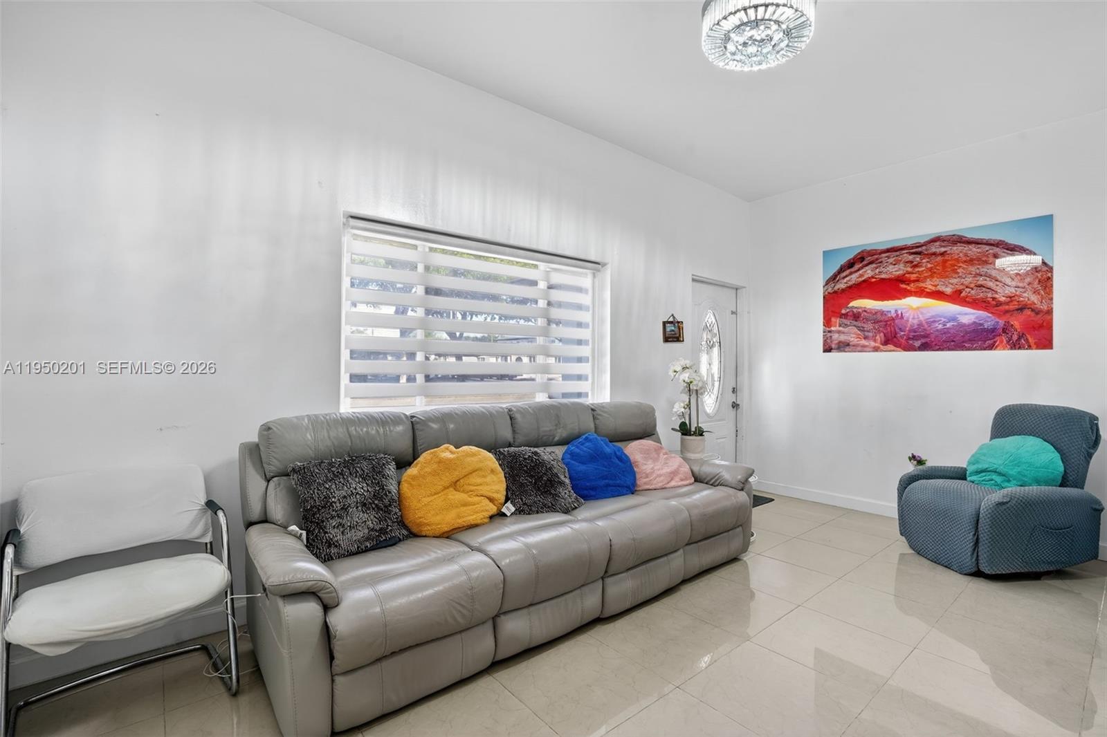 A living room features a grey leather sofa, a blue recliner, and tile flooring — 1240 Sharazad Blvd, Opa-Locka FL 33054, OPA-LOCKA, FL
