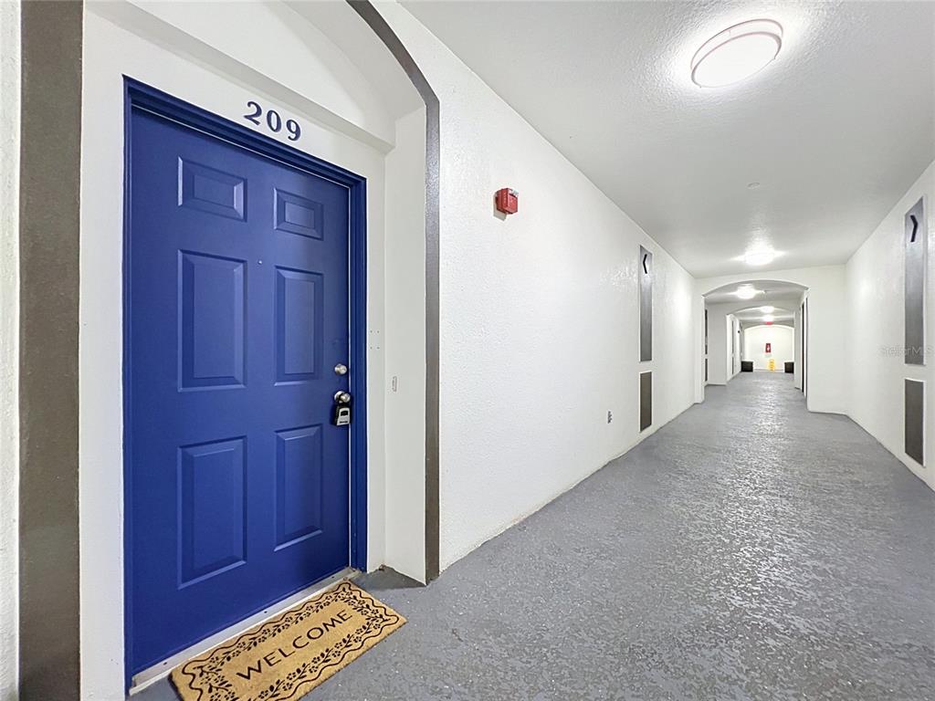A blue apartment door labeled 209 sits at the end of a long hallway — 4024 BREAKVIEW DRIVE UNIT 20904, ORLANDO, FL