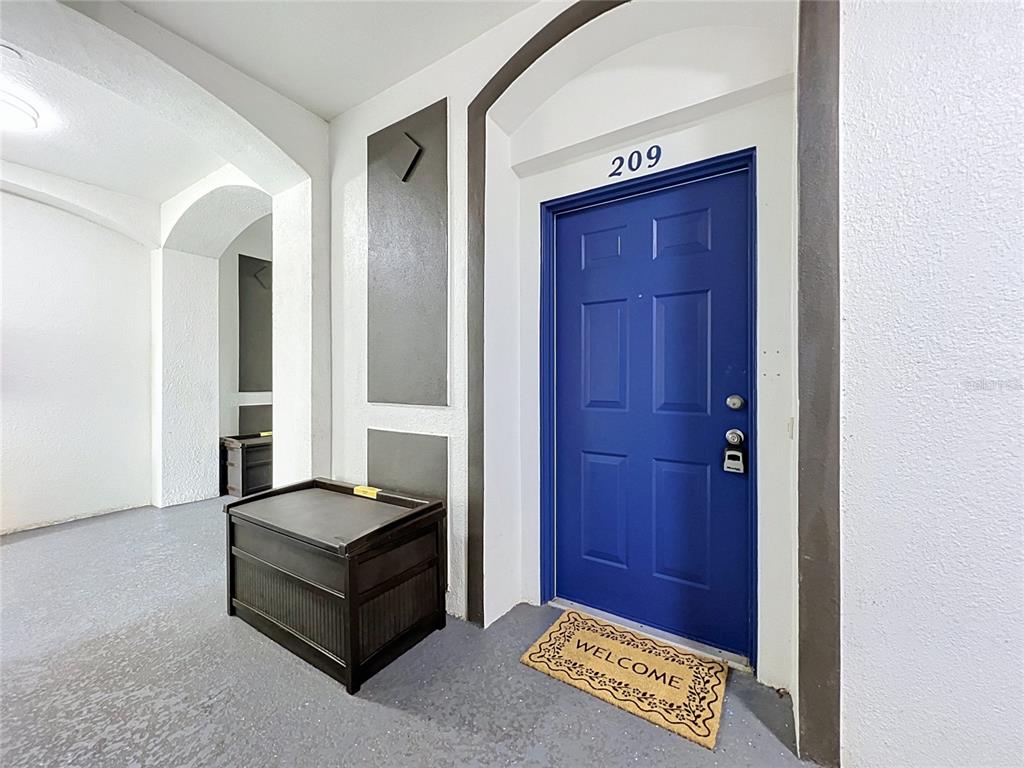 A blue front door labeled 209 sits in a hallway with a storage bench and mat — 4024 BREAKVIEW DRIVE UNIT 20904, ORLANDO, FL