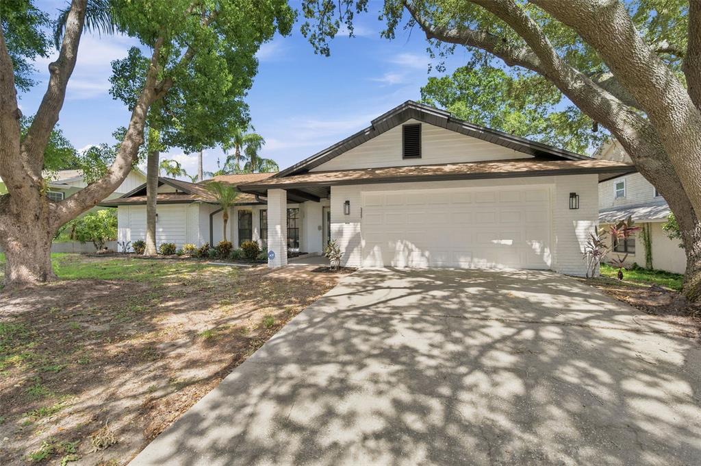 A single-story white brick house with a two-car garage and large shade trees — 2721 BRIARPATCH DRIVE, VALRICO, FL