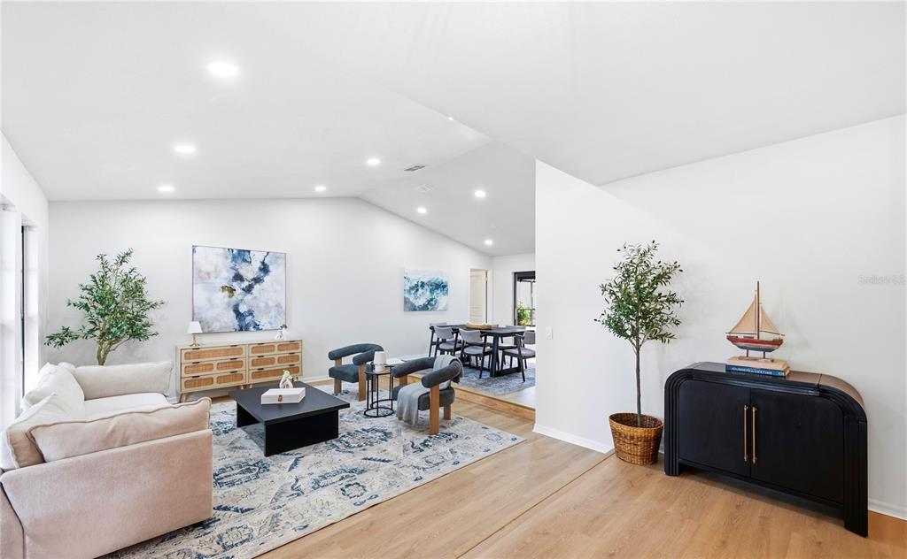 A living room with a beige sofa, patterned rug, and a dining area in the background — 2721 BRIARPATCH DRIVE, VALRICO, FL