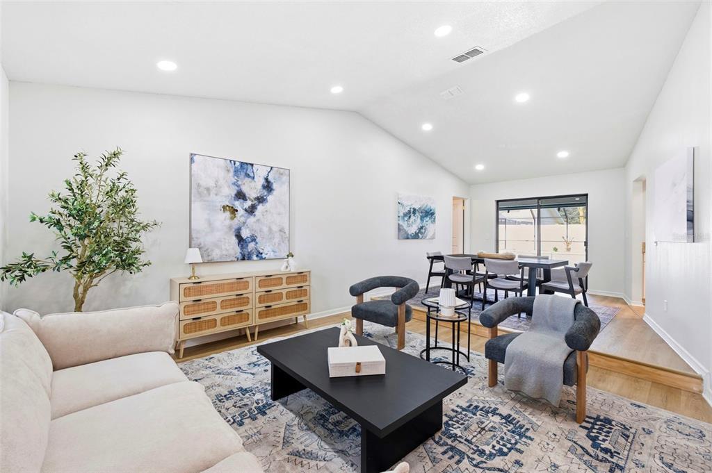 A living room with a vaulted ceiling, a beige sofa, two armchairs, and a dining area — 2721 BRIARPATCH DRIVE, VALRICO, FL
