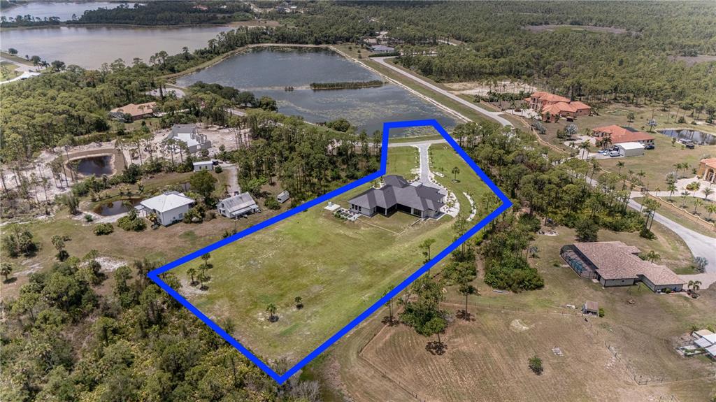 An aerial view shows a house with a dark roof situated on a large lot — 9240 FALCON COURT, VENICE, FL