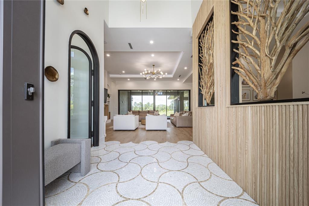A modern entryway features a patterned tile floor, wood-paneled wall, and a view into the living room — 9240 FALCON COURT, VENICE, FL