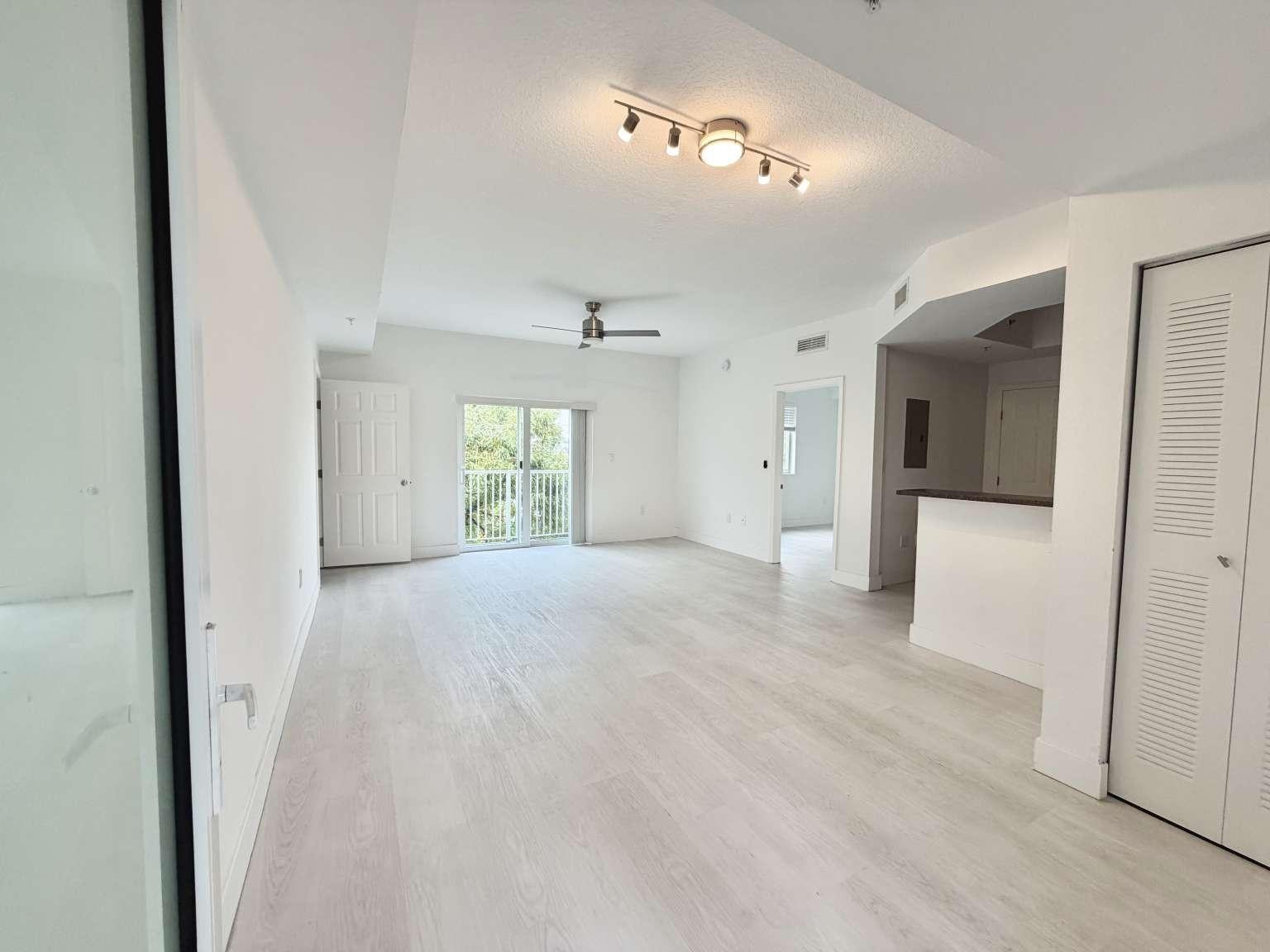 An open-concept living area features light wood-look flooring, a ceiling fan, and a sliding glass door — 7516 NE 1st Avenue # 302, Miami FL 33138, MIAMI, FL