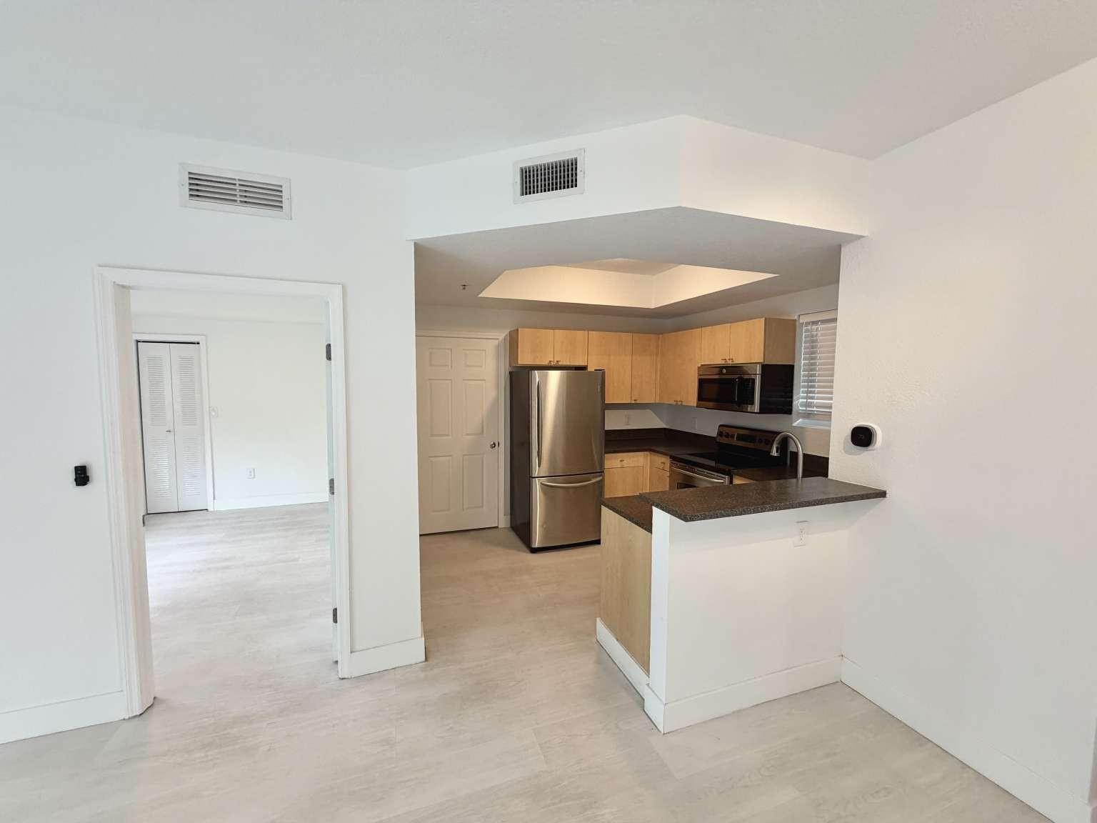 A kitchen with light wood cabinets and stainless steel appliances opens to a living area — 7516 NE 1st Avenue # 302, Miami FL 33138, MIAMI, FL