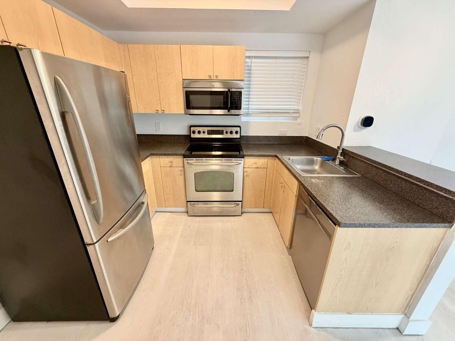 A kitchen features light wood cabinets, stainless steel appliances, and dark countertops — 7516 NE 1st Avenue # 302, Miami FL 33138, MIAMI, FL