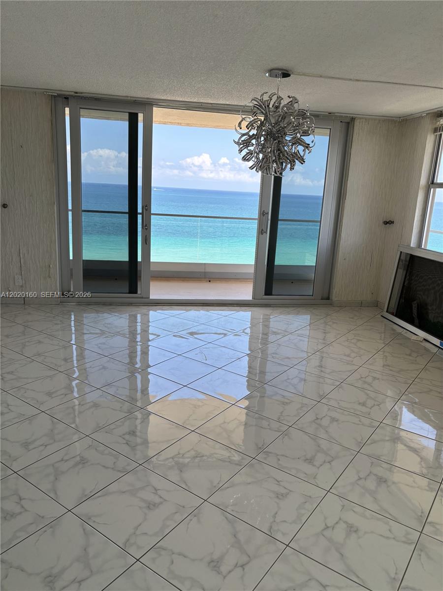 A room with white marble-patterned tile floors and a sliding glass door overlooking the ocean — 1920 S Ocean Dr # 16B, Hallandale Beach FL 33009, HALLANDALE BEACH, FL