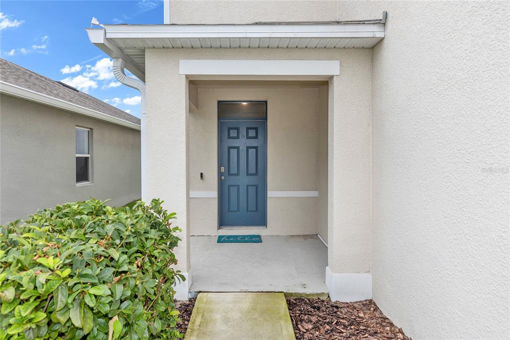 A blue front door is set within a covered entryway of a stucco house — 3758 SUNGROVE CIRCLE, SANFORD, FL