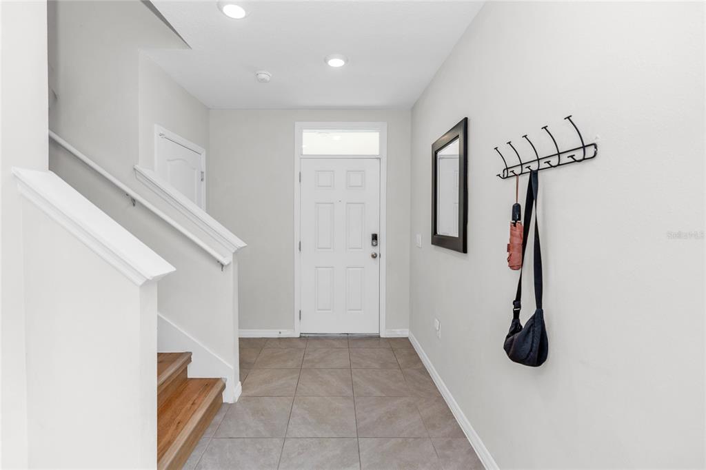 An entryway features a white front door, tiled flooring, a staircase, and a wall-mounted rack — 3758 SUNGROVE CIRCLE, SANFORD, FL
