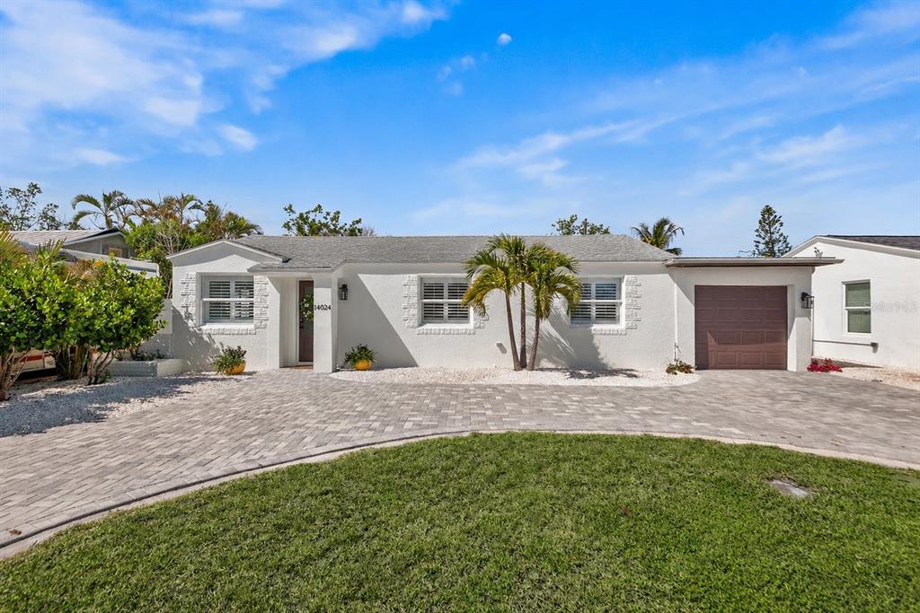 A single-story white house with a paved driveway, a garage, and a palm tree — 14024 N BAYSHORE DRIVE, MADEIRA BEACH, FL