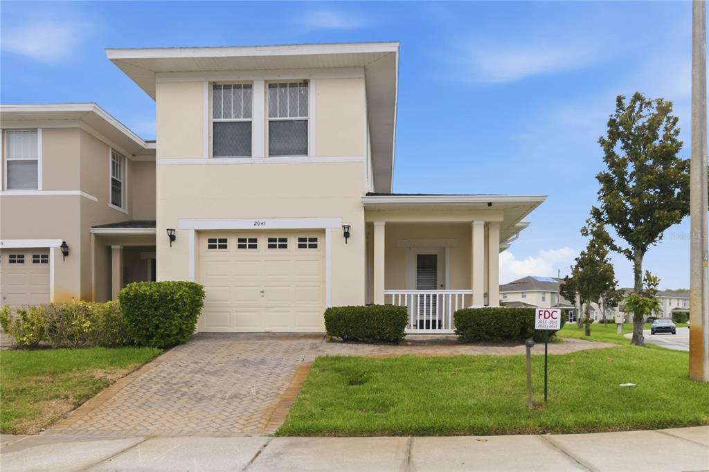 A two-story townhouse with a single-car garage, a front porch, and a paved driveway — 2041 LACIE JO LANE, KISSIMMEE, FL
