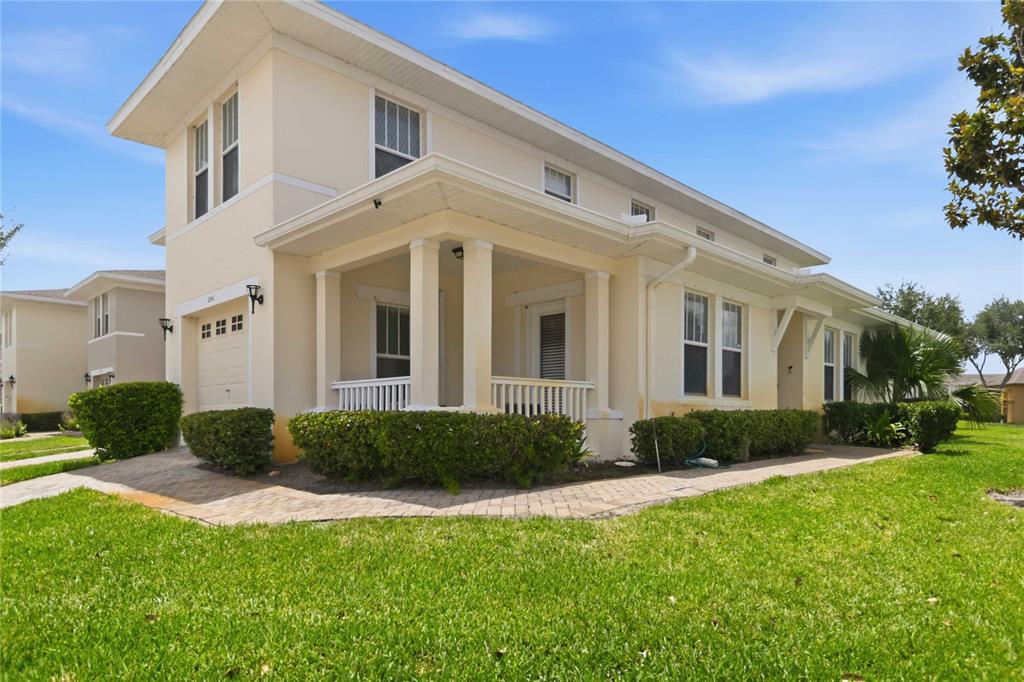 A two-story house with a beige exterior, a covered front porch, and a paved walkway — 2041 LACIE JO LANE, KISSIMMEE, FL