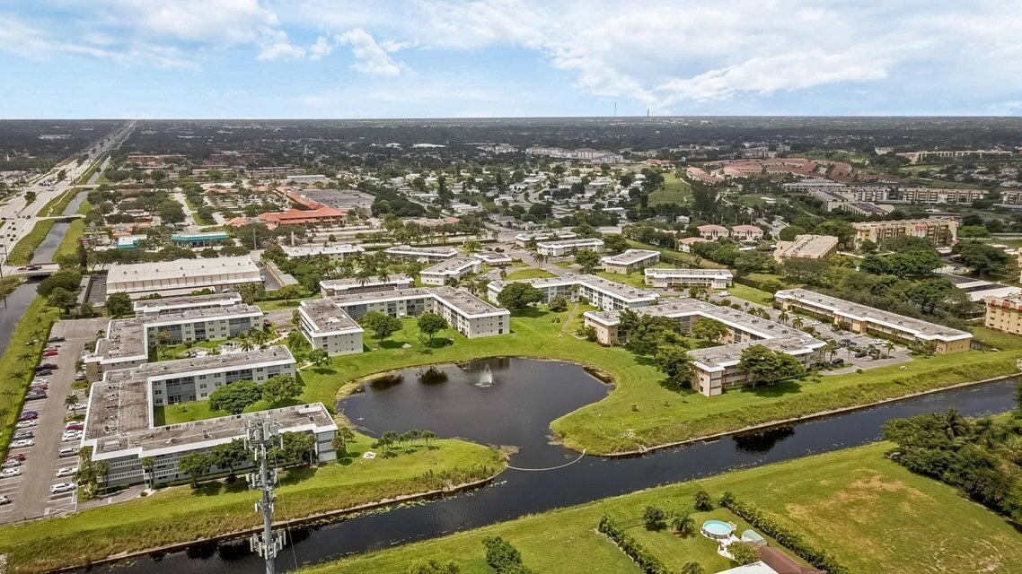 An aerial view shows a multi-building apartment complex surrounding a pond with a fountain — 9826 Marina Boulevard # 1015, Boca Raton FL 33428, BOCA RATON, FL