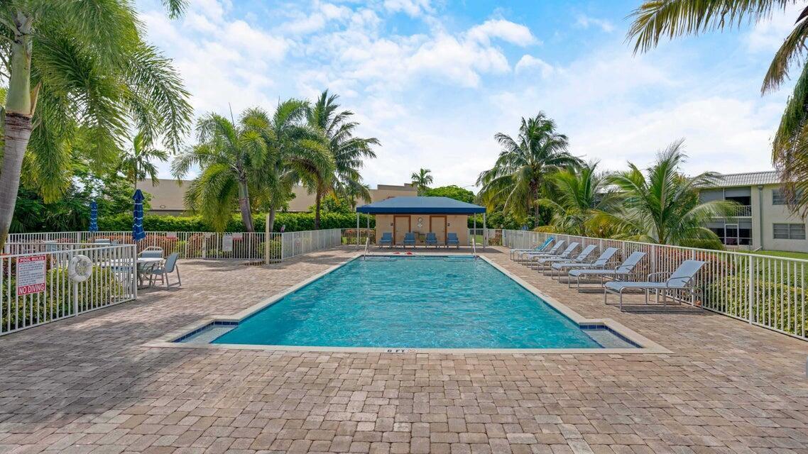 A rectangular swimming pool surrounded by a brick patio, lounge chairs, and palm trees — 9826 Marina Boulevard # 1015, Boca Raton FL 33428, BOCA RATON, FL