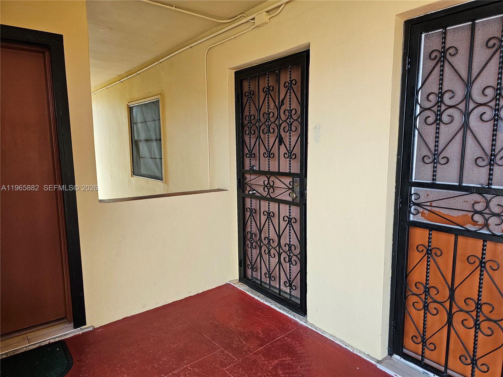 A covered outdoor walkway features red tile flooring and two doors with black security grilles — 47 NW 47th Ave # 16, Miami FL 33126, MIAMI, FL