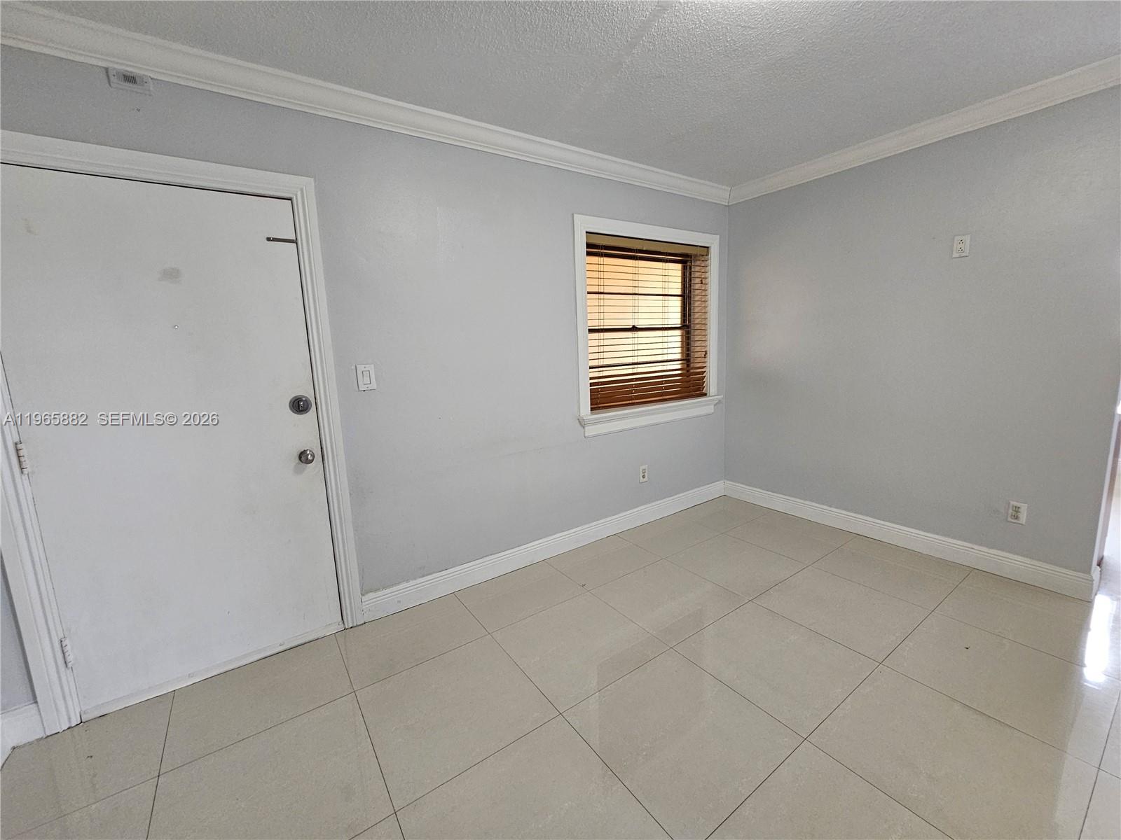 An empty room features light gray walls, white trim, and large beige floor tiles — 47 NW 47th Ave # 16, Miami FL 33126, MIAMI, FL