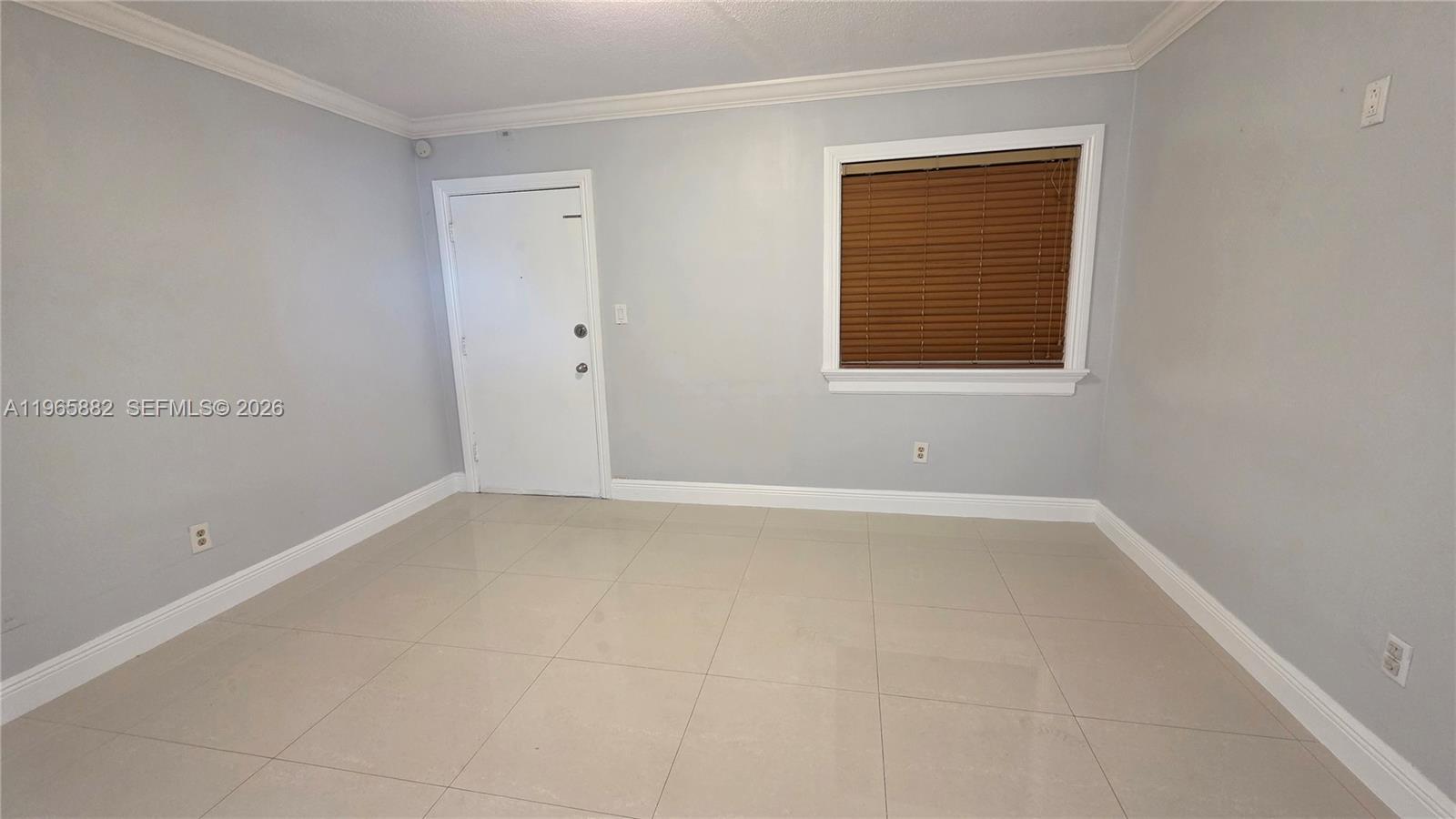 An empty room features light gray walls, large beige floor tiles, and a white door — 47 NW 47th Ave # 16, Miami FL 33126, MIAMI, FL