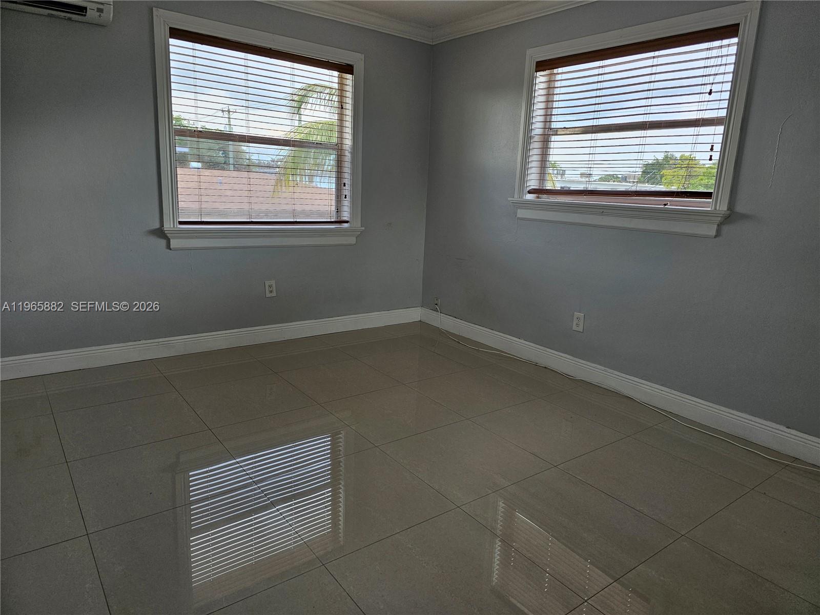 An empty room features gray walls, large beige floor tiles, and two windows with blinds — 47 NW 47th Ave # 16, Miami FL 33126, MIAMI, FL