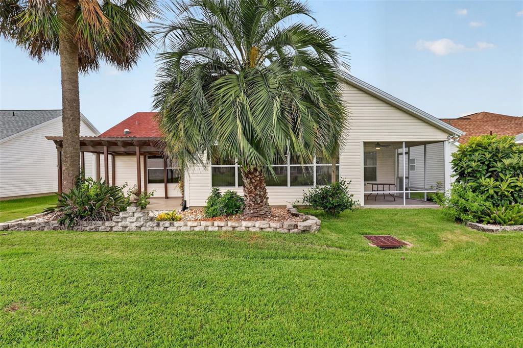 The exterior of a house features a palm tree, a pergola, and a screened-in porch — 2129 MARGARITA DRIVE, THE VILLAGES, FL