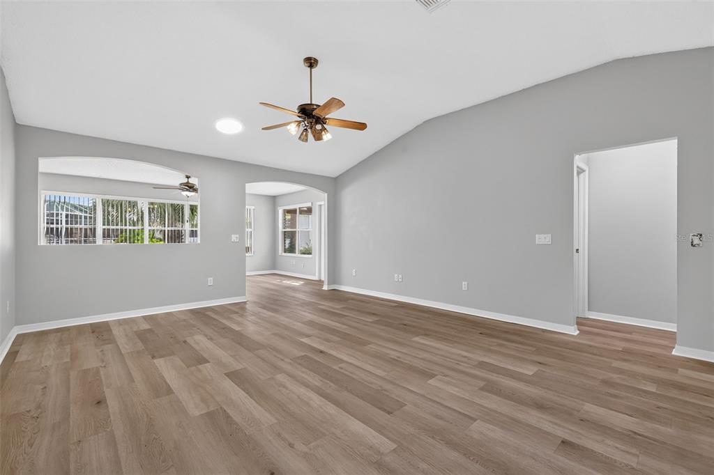 An empty living room with light gray walls, wood-look flooring, and a vaulted ceiling — 2129 MARGARITA DRIVE, THE VILLAGES, FL