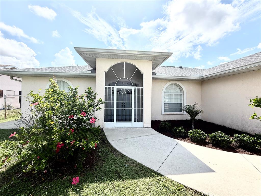 The exterior of a single-story house features a white arched entryway and a concrete walkway — 219 VENETIA AVENUE, NORTH PORT, FL