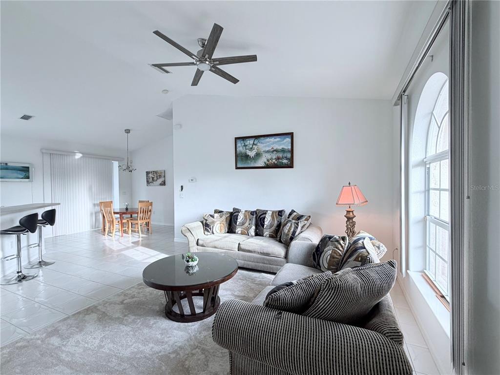 A living room features a sofa, loveseat, glass coffee table, ceiling fan, and tiled floors — 219 VENETIA AVENUE, NORTH PORT, FL