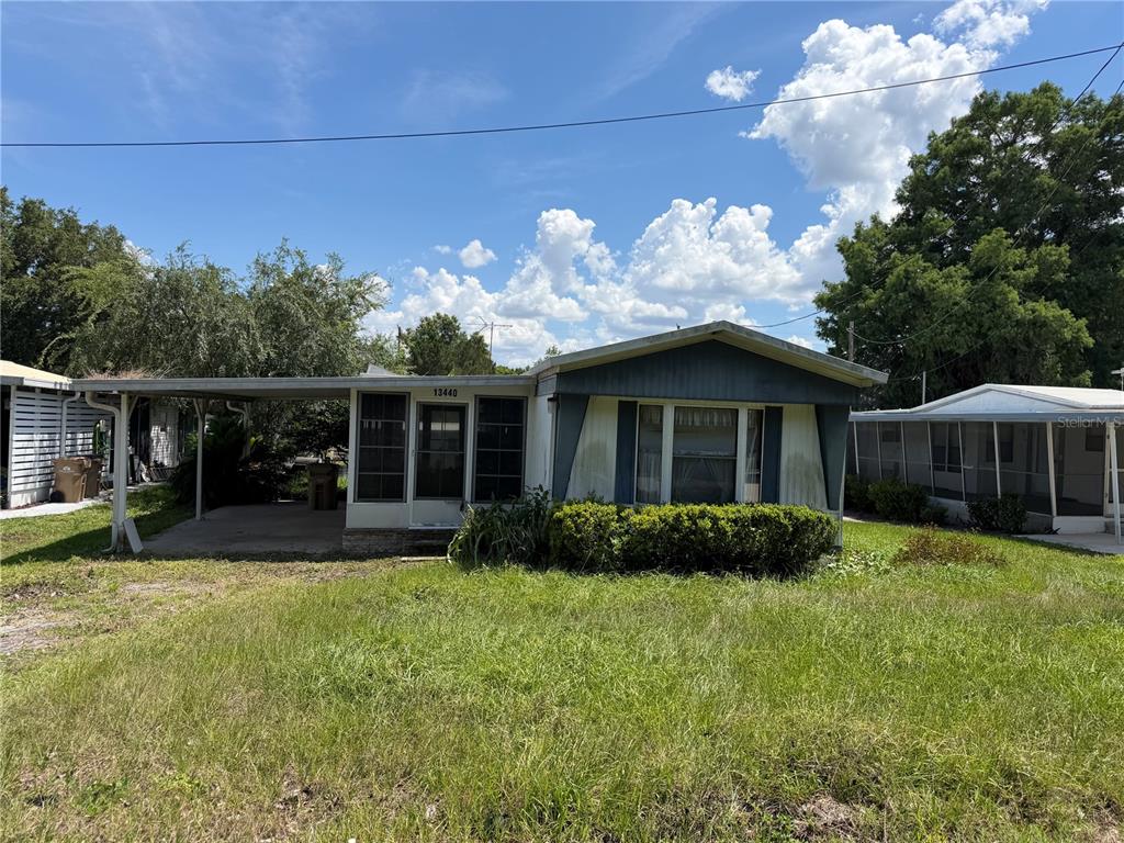 A single-story manufactured home with a carport and a screened-in front porch — 13440 PALM DRIVE UNIT 7, ASTATULA, FL