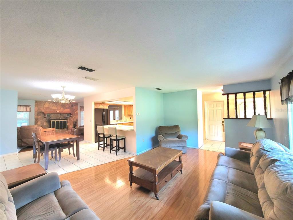 An open-concept living and dining area features wood flooring, a stone fireplace, and kitchen island — 19725 SW BEACH BOULEVARD, DUNNELLON, FL