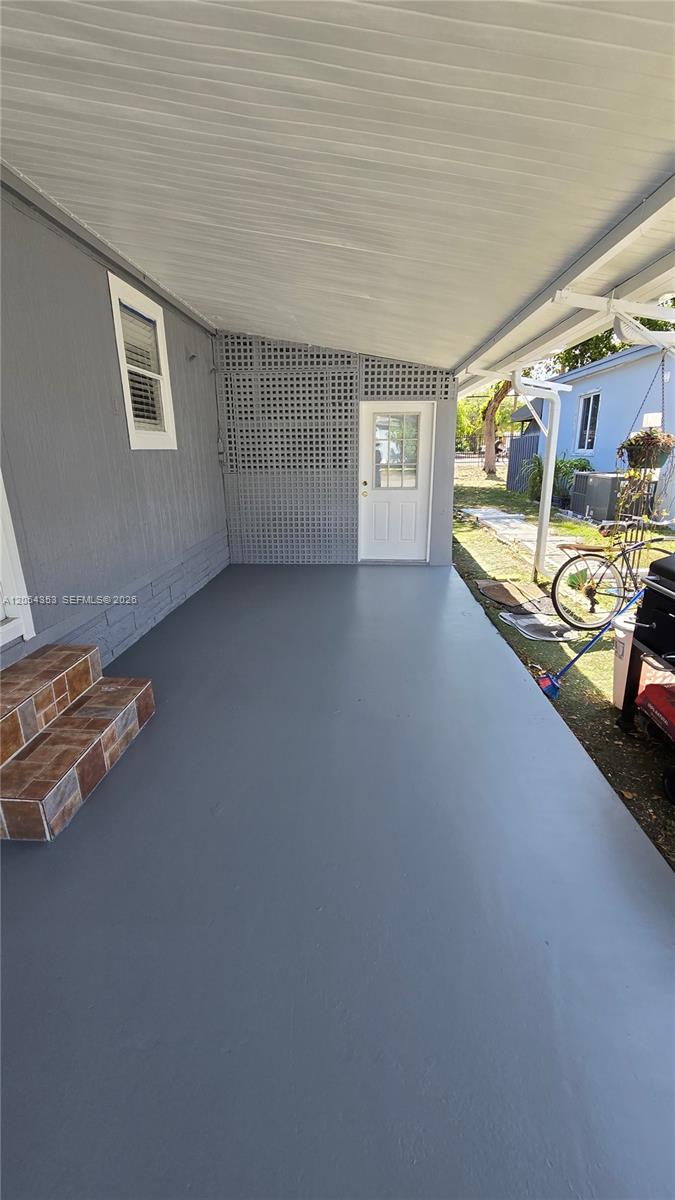 A covered patio features a gray painted floor, tiled steps, and a white exterior door — 20016 NW 56 Ave, Miami Gardens FL 33055, MIAMI GARDENS, FL
