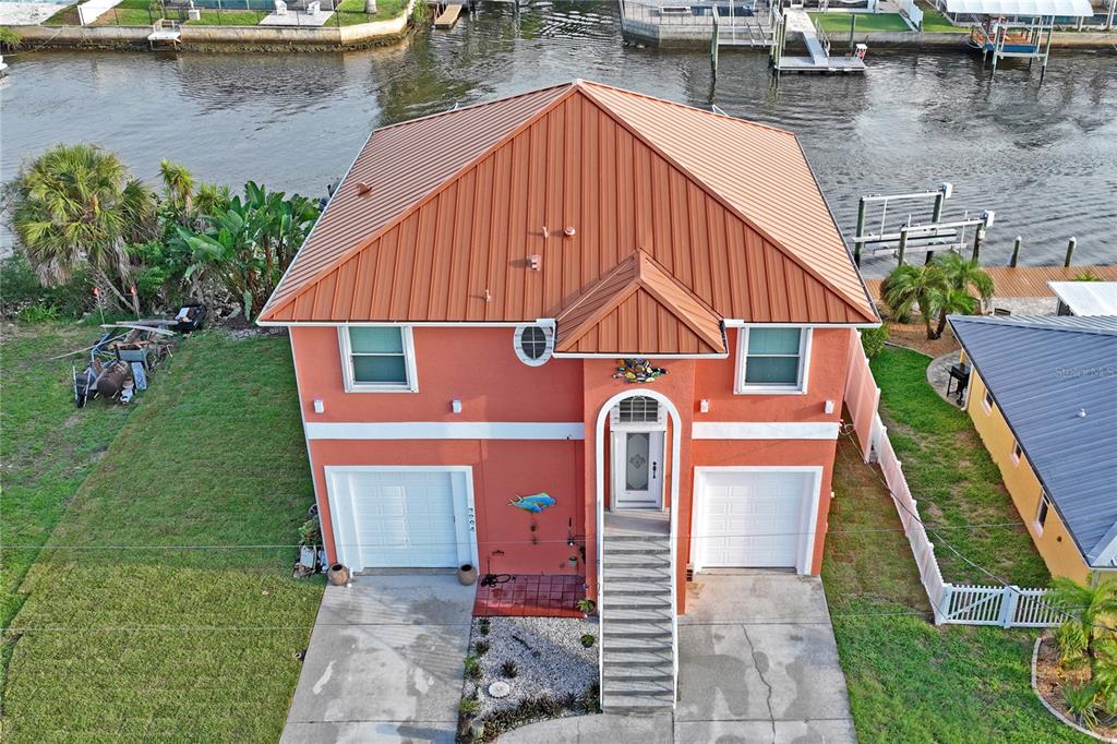 An aerial view of a two-story orange house with a metal roof and two garages — 3294 MINNOW CREEK DRIVE, HERNANDO BEACH, FL