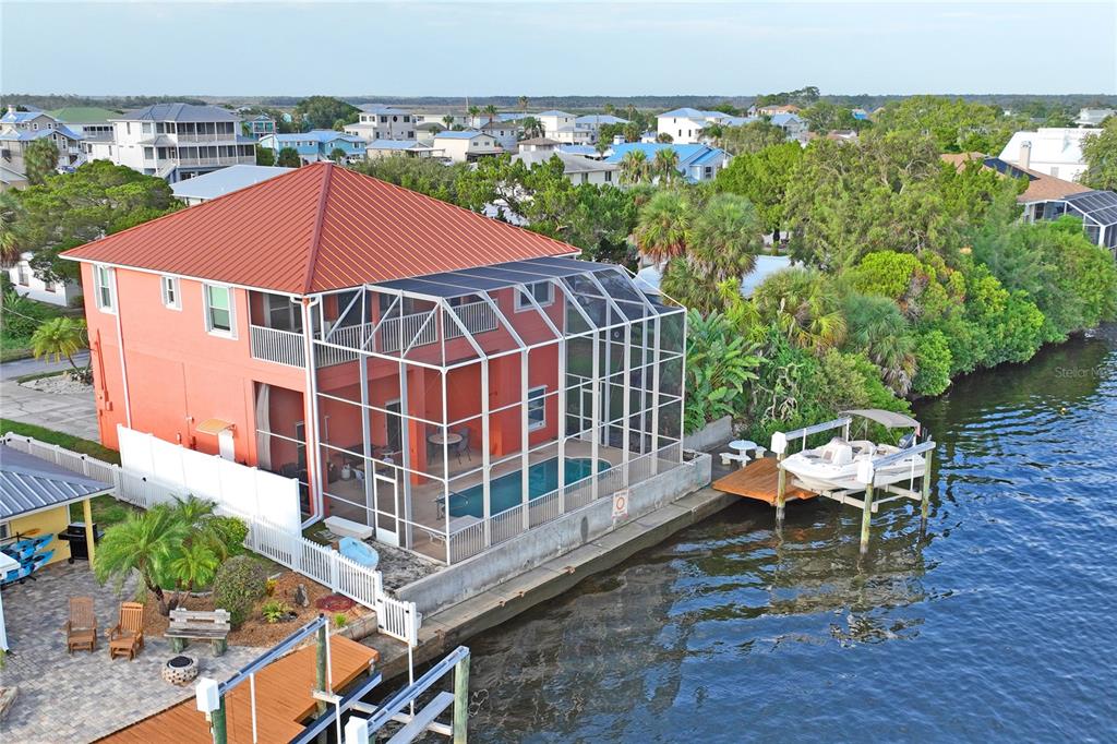 An aerial view of a two-story orange house with a screened-in pool and private dock — 3294 MINNOW CREEK DRIVE, HERNANDO BEACH, FL