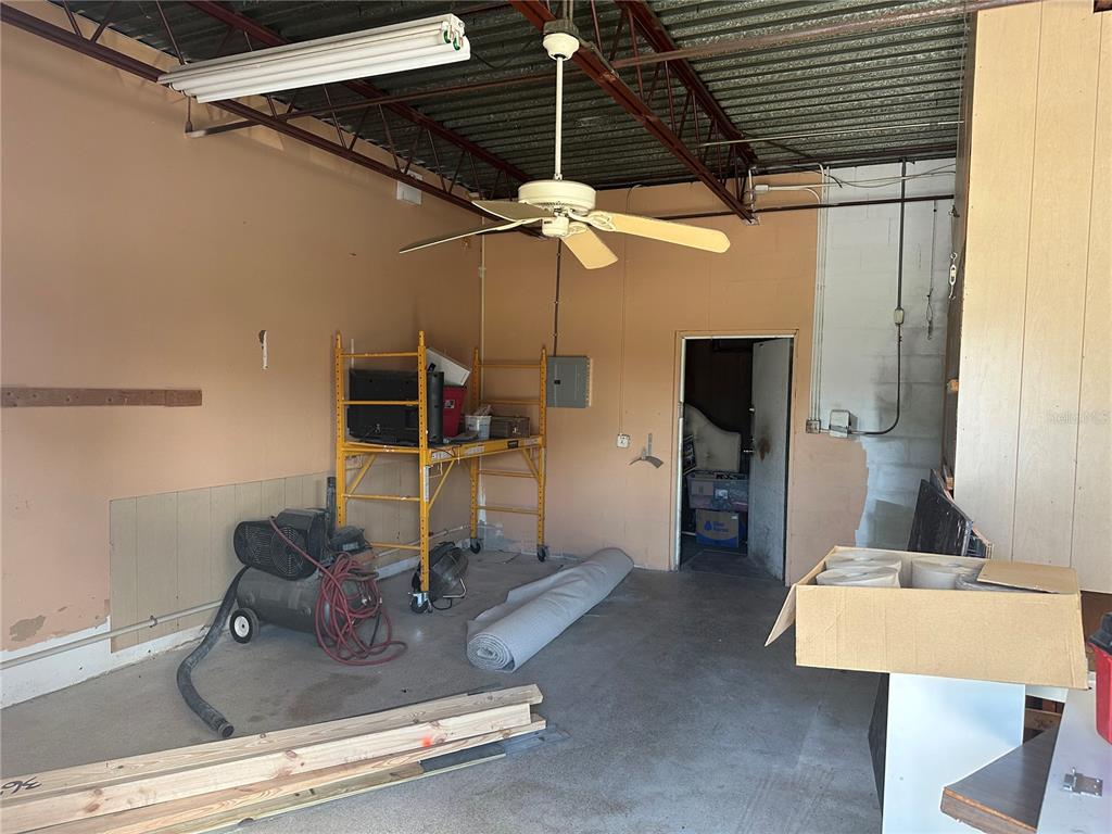 An unfinished garage features a ceiling fan, a yellow metal scaffold, and concrete flooring — 2254 S TAMIAMI TRAIL, VENICE, FL