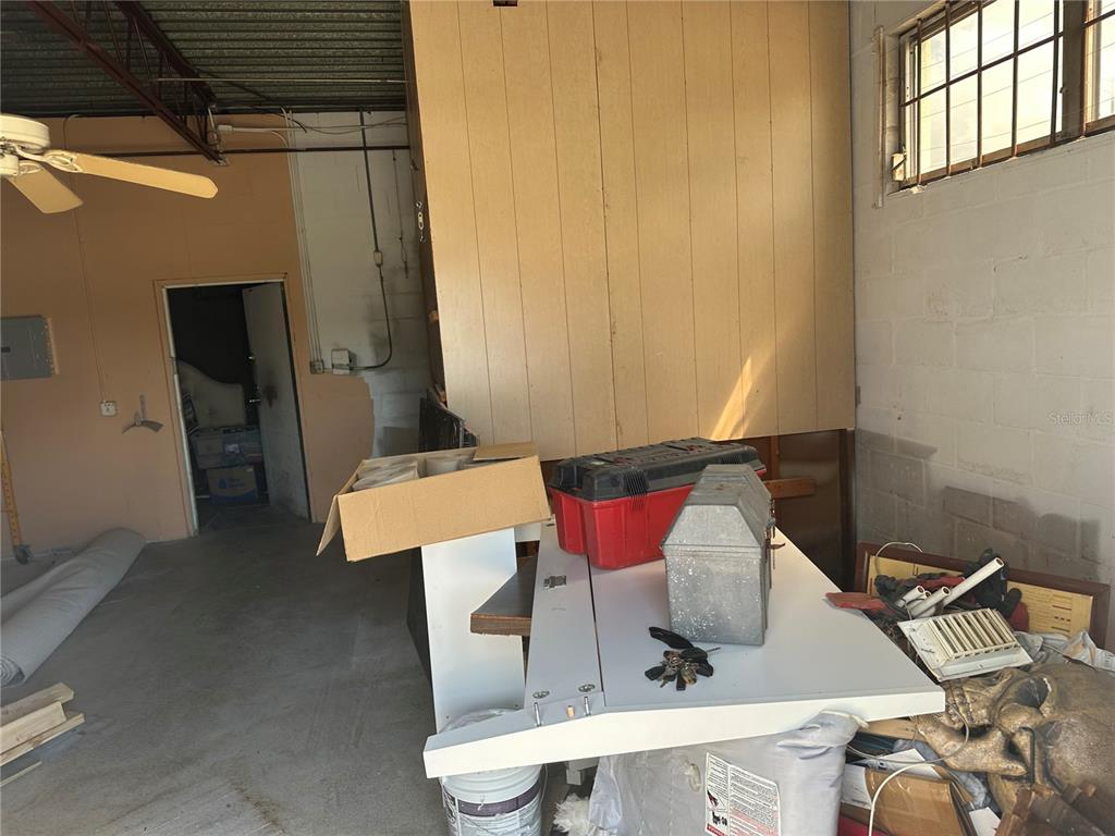 A cluttered garage features a wood-paneled wall, a workbench, and a ceiling fan — 2254 S TAMIAMI TRAIL, VENICE, FL
