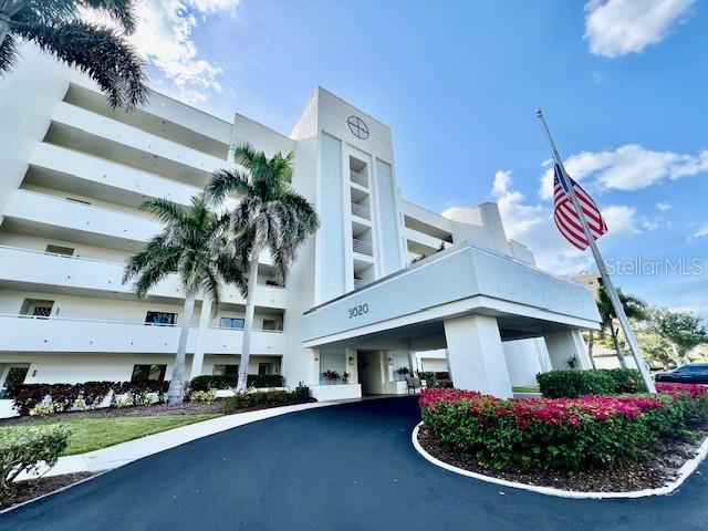 A multi-story white apartment building is surrounded by palm trees and green landscaping — 3020 MATECUMBE KEY ROAD UNIT 103, PUNTA GORDA, FL