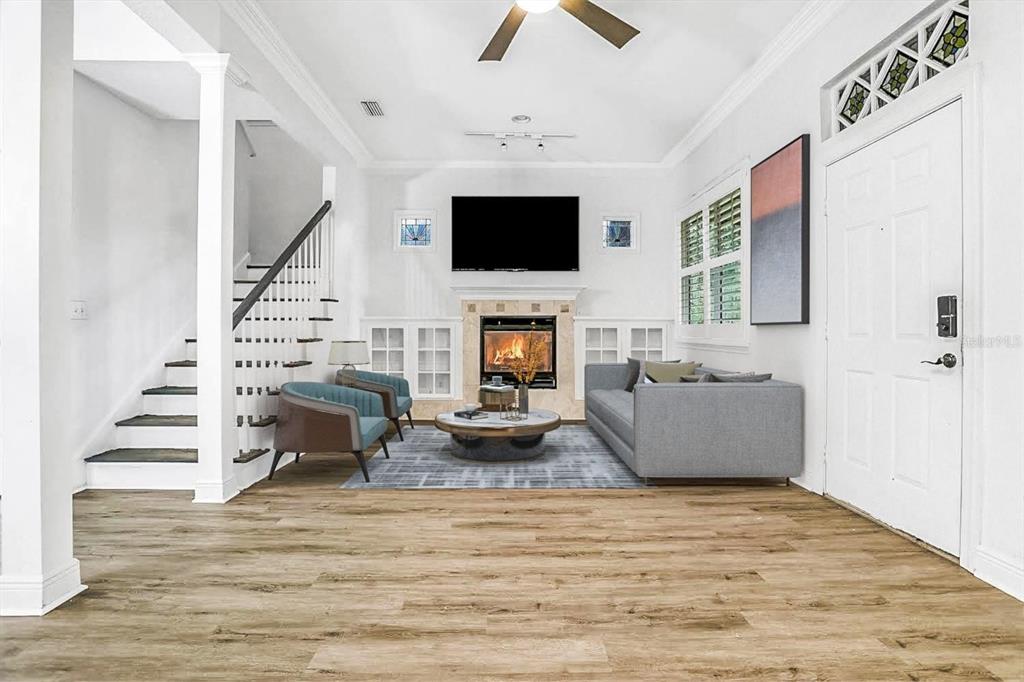 A living room features a fireplace, a mounted television, a staircase, and light wood flooring — 148 S THORNTON AVENUE, ORLANDO, FL