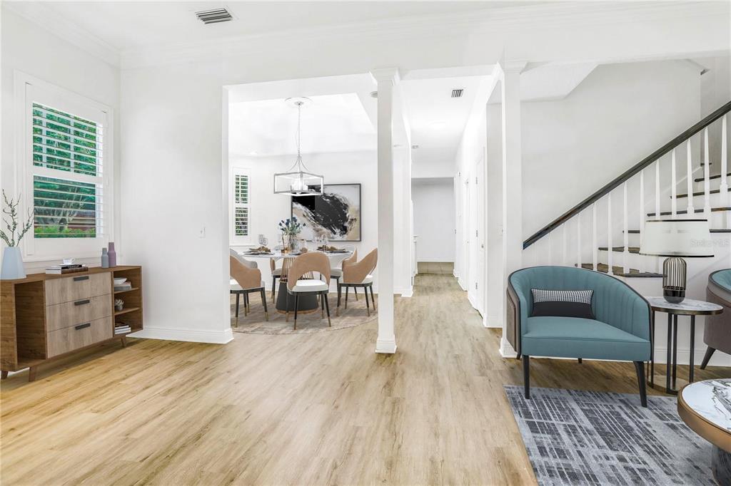 A bright living area with wood-look flooring leads to a dining room and staircase — 148 S THORNTON AVENUE, ORLANDO, FL