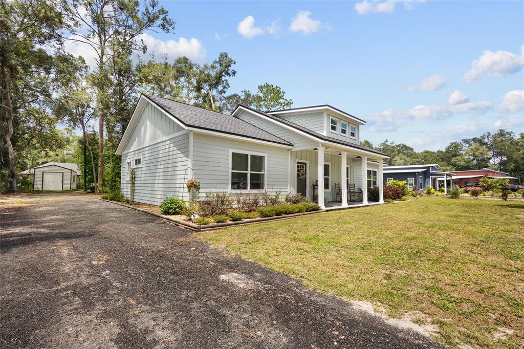 A light-colored house with a covered front porch sits on a large, grassy lot — 8071 NW 172ND LANE, TRENTON, FL