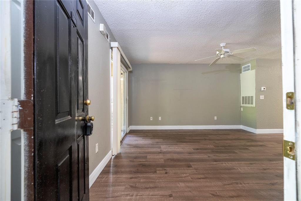 An interior view of an empty room with wood-look flooring, a ceiling fan, and sliding doors — 2210 YANKEE PLACE UNIT 316, ORLANDO, FL