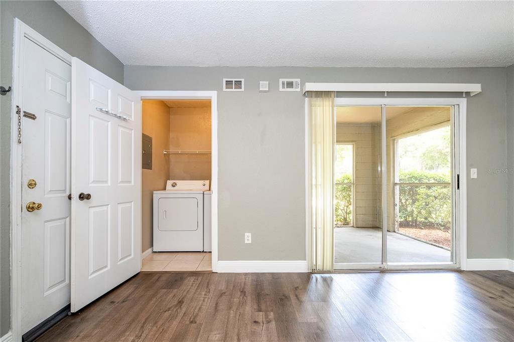 A room with wood-look flooring, a laundry closet, and a sliding glass door to a patio — 2210 YANKEE PLACE UNIT 316, ORLANDO, FL