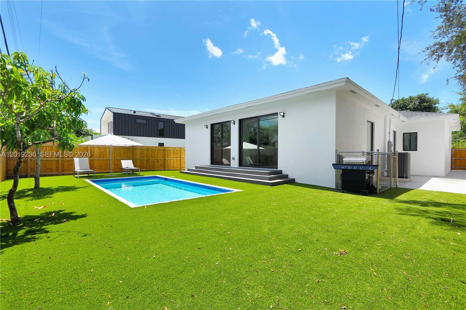 A white house with a swimming pool and artificial turf lawn in the backyard — 2001 SW 22nd Ter, Miami FL 33145, MIAMI, FL