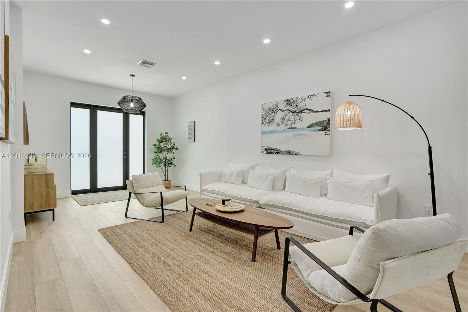 A bright living room features a white sofa, two armchairs, a wooden coffee table, and artwork — 2001 SW 22nd Ter, Miami FL 33145, MIAMI, FL