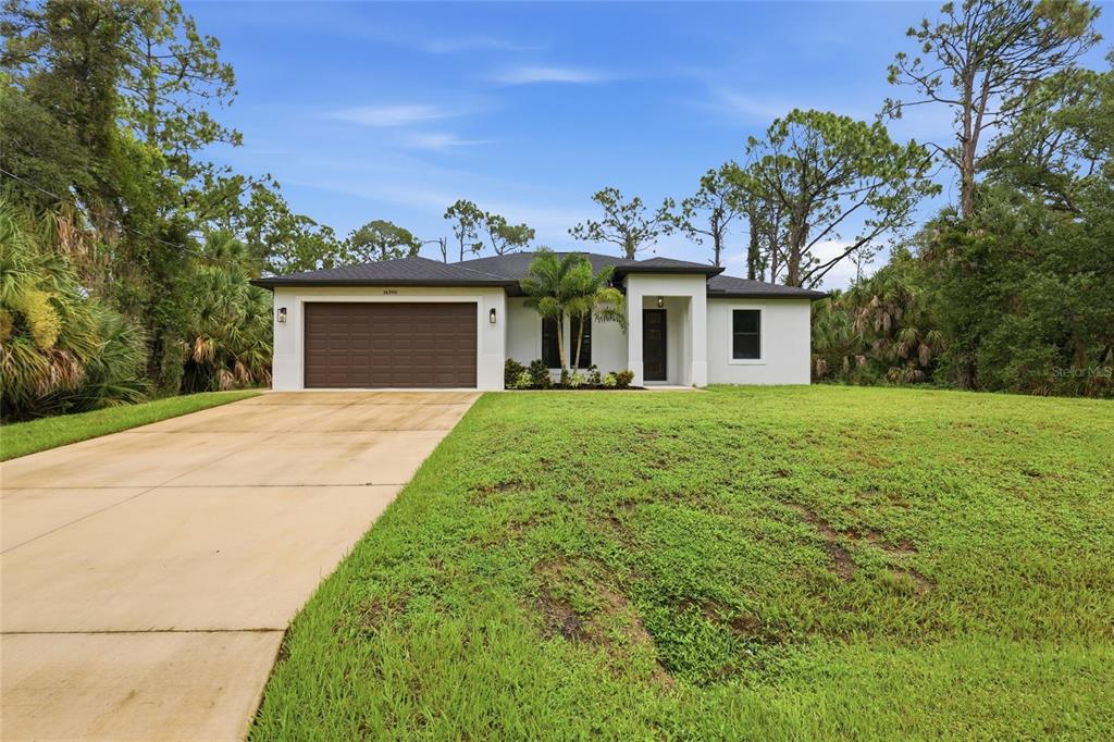 A single-story house with a white exterior, brown garage door, and a concrete driveway — 14390 MADDOCK AVENUE, PORT CHARLOTTE, FL